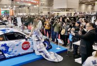 Booth NMAA Great of Indonesia menjadi pusat perhatian di Osaka Auto Messe 2026, Jepang. Toyota 86 “Harmony of Waves” tampil memukau dengan livery bernuansa ombak dipadukan gaun batik karya desainer Indonesia, saat dikelilingi fotografer dan pengunjung yang mengabadikan momen.