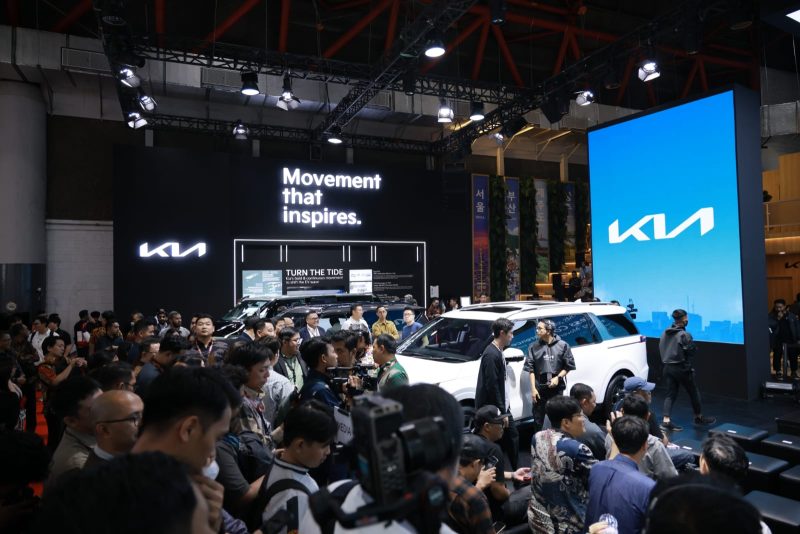 Booth Kia dipadati pengunjung dalam sebuah pameran otomotif, menampilkan lini kendaraan terbaru dengan slogan “Movement that inspires.”