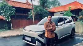 Seorang konsumen berpose di depan Kia Carens usai penggunaan harian dan perjalanan jarak menengah, menyoroti kenyamanan kabin serta fitur yang mendukung mobilitas keluarga.