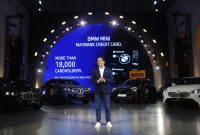 President Director BMW Group Indonesia Sunny Medalla saat tampil dalam acara BMW Group Indonesia bersama Maybank. Di belakangnya terlihat jajaran kendaraan BMW dan MINI, termasuk New BMW iX3 dan MINI Aceman, yang menjadi bagian dari dukungan mobilitas berkelanjutan Maybank Marathon 2026.