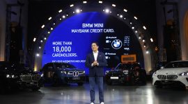 President Director BMW Group Indonesia Sunny Medalla saat tampil dalam acara BMW Group Indonesia bersama Maybank. Di belakangnya terlihat jajaran kendaraan BMW dan MINI, termasuk New BMW iX3 dan MINI Aceman, yang menjadi bagian dari dukungan mobilitas berkelanjutan Maybank Marathon 2026.