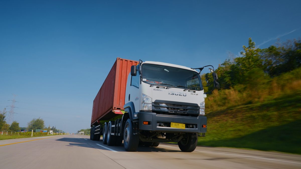 Isuzu GIGA mengangkut kontainer melaju di jalan tol, menjadi salah satu kendaraan komersial yang mendukung aktivitas logistik dan distribusi barang di Indonesia.