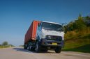 Isuzu GIGA mengangkut kontainer melaju di jalan tol, menjadi salah satu kendaraan komersial yang mendukung aktivitas logistik dan distribusi barang di Indonesia.
