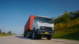 Isuzu GIGA mengangkut kontainer melaju di jalan tol, menjadi salah satu kendaraan komersial yang mendukung aktivitas logistik dan distribusi barang di Indonesia.