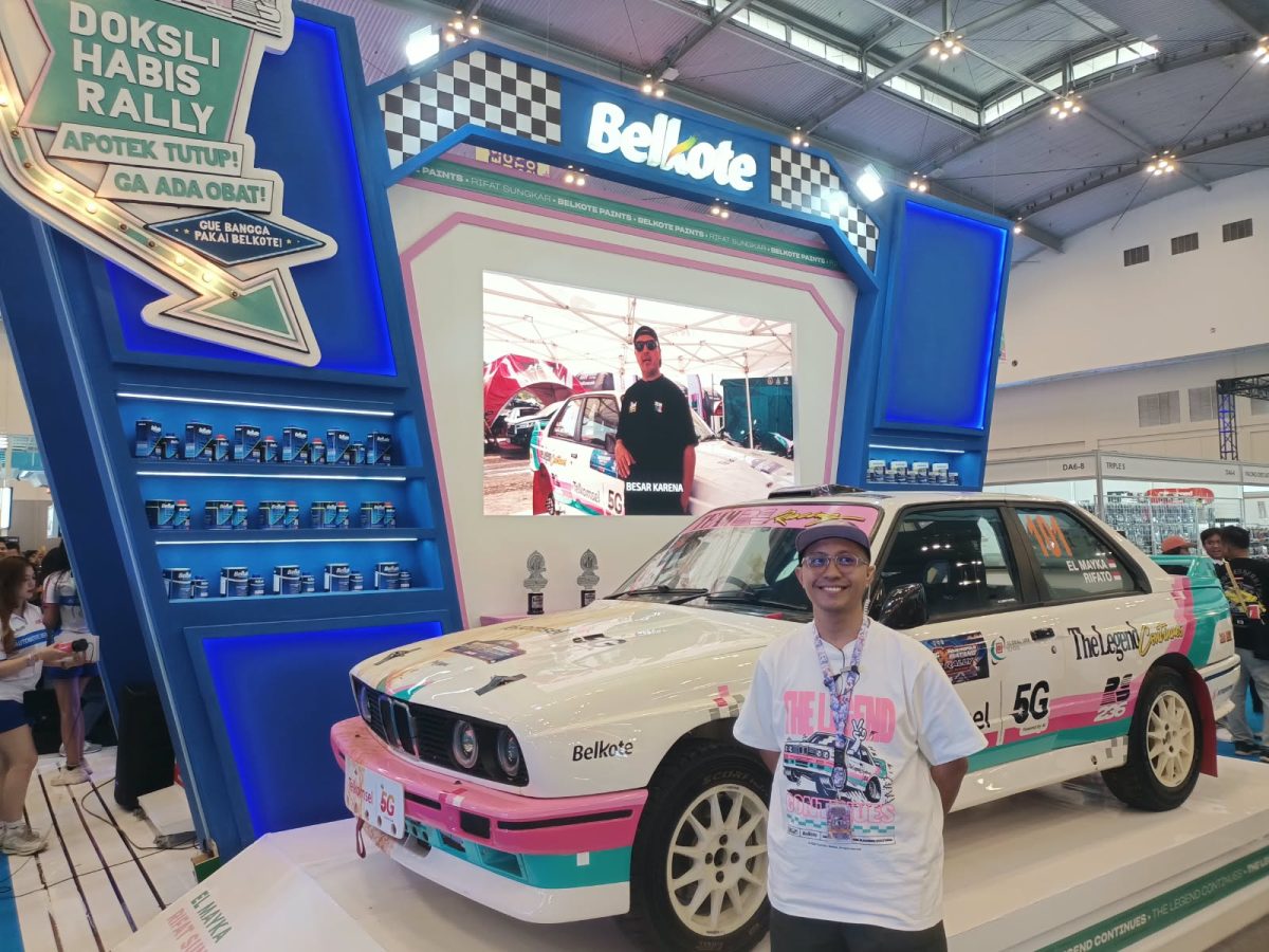 Brand Strategi Belkote, Gimy Bayu, berpose di depan mobil reli milik Rifat Sungkar yang menggunakan cat Belkote di booth IMX 2026, Jumat (9/10/2026).