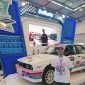 Brand Strategi Belkote, Gimy Bayu, berpose di depan mobil reli milik Rifat Sungkar yang menggunakan cat Belkote di booth IMX 2026, Jumat (9/10/2026).