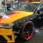 Keterangan Foto: Mobil modifikasi berbalut warna Obsidian Black dengan kombinasi grafis kuning, oranye, dan merah tampil di booth Penta Prima Paint pada ajang IMX 2026 di Tangerang. Finishing hitam mengilap dipadukan dengan velg sporty beraksen merah, memperkuat karakter agresif kendaraan.